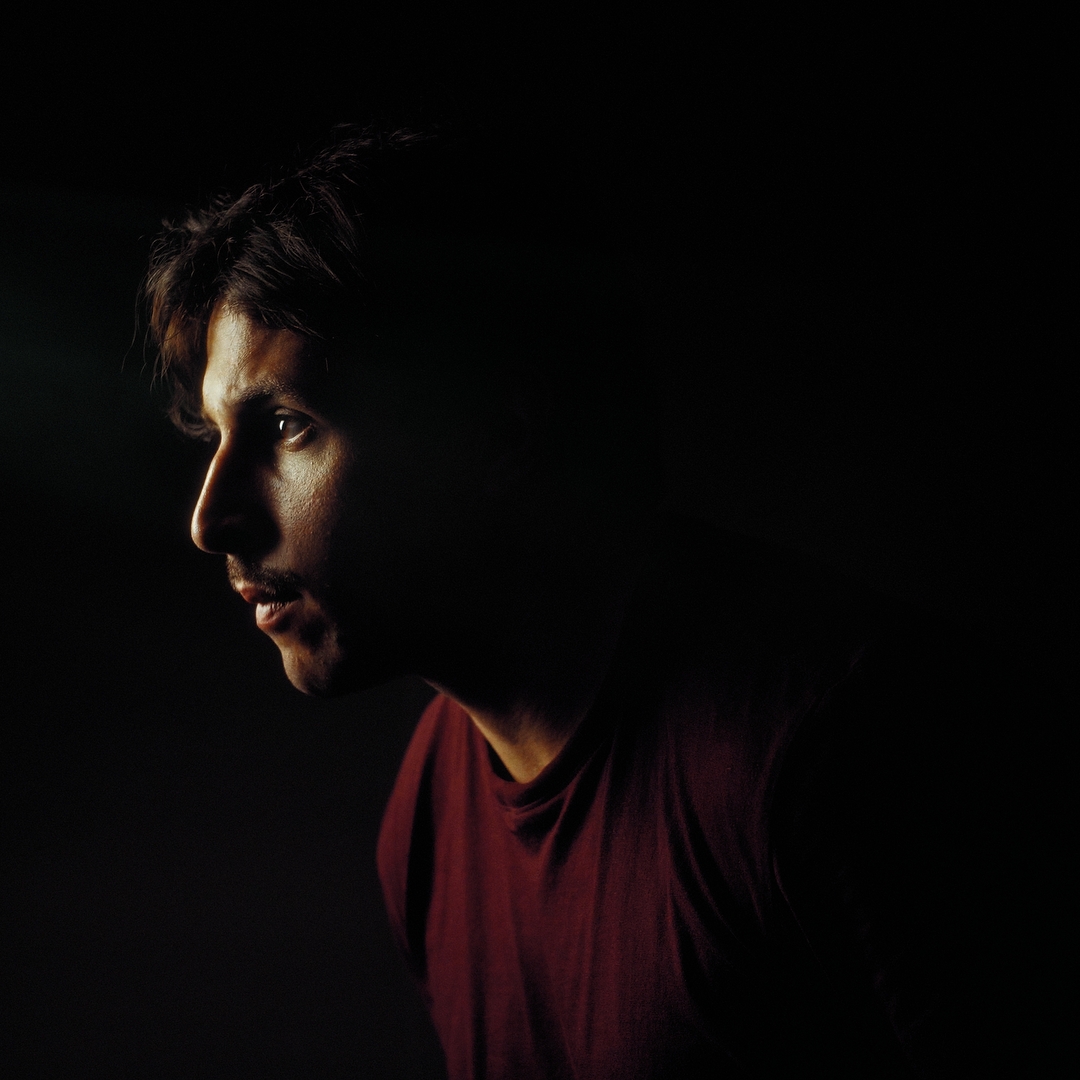 Maikon Winter in a red shirt, lit against a dark background